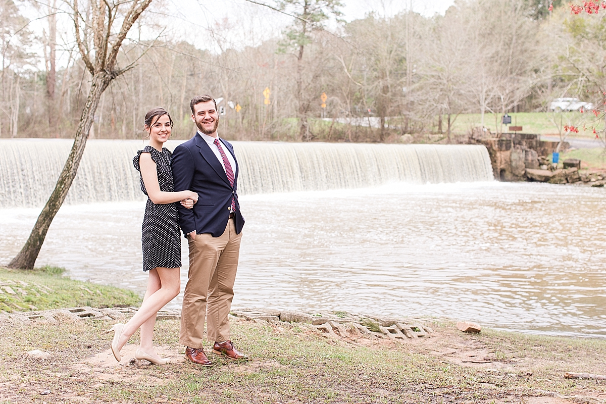 Couple poses near waterfall during engagement session at Starrs Mill Park
